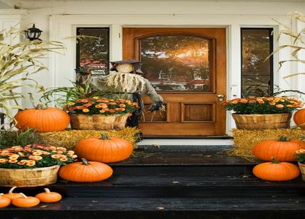 Large wood front entry door, plants and fall decorations on front porch
