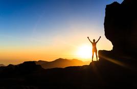 Client picture of person in sunlight on top of mountain with arms stretched: Janice N.