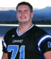 Senior picture of Sean, wearing high school football jersey number 71, smiling, looking at camera with lake & mountains in background.