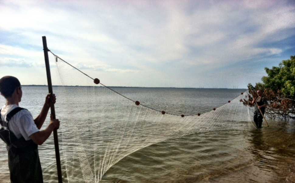 Boy and Man holding a long seine net with pole at the edge of the beach in Florida