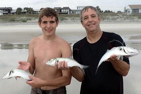 Two men holding 3 fish caught in seine