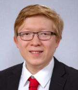 Head-shot of Ian, smiling, looking at camera, wearing suit and tie