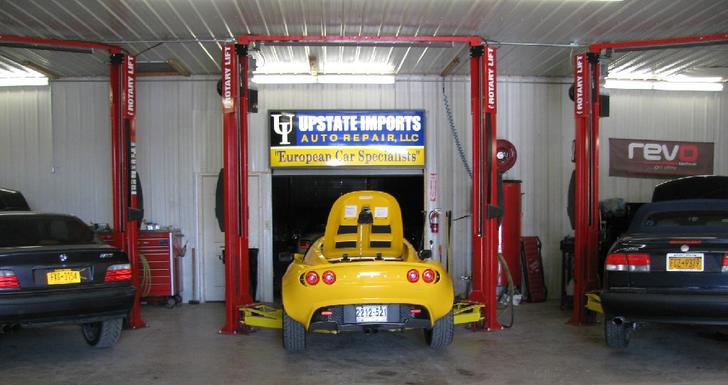 Two black and one yellow forgein vehicles being worked on at Upstate Imports in Syracuse, NY