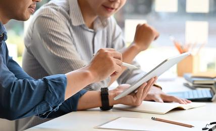 Two men in a meeting looking at a tablet