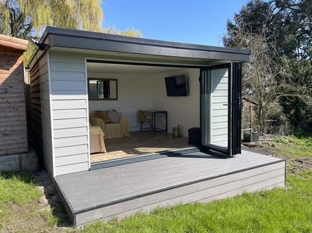 Grey slatted garden building with open bifold doors