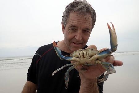 Man holding a live blue crab on beach