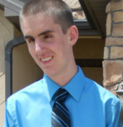 Outdoor picture of Cody, wearing shirt and tie, smiling at camera.