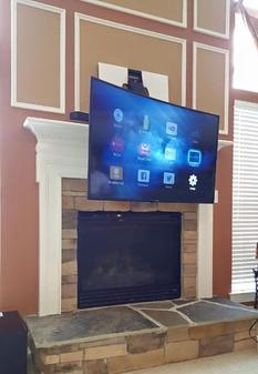 Carolina Custom Mounts of Charlotte Flat screen tv mounting services.  Picture of Curved TV mounted over Fireplace with pull down fireplace mount.