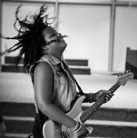 Teen girl flipping her hair while playing an electric guitar
