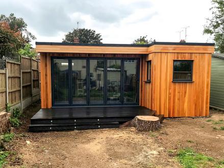 Modern cedar clad garden room with 5 panel bifold doors and 2 small windows