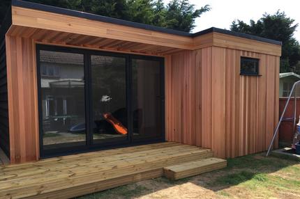 Modern cedar clad garden room 3 panel bifold doors and small window