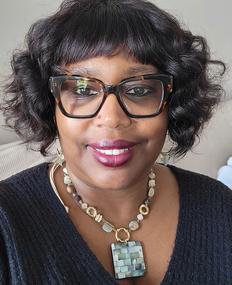 Image of stylish Black woman named Anita Godfrey wearing glasses and statement necklace