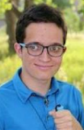 Outdoor picture of Caleb smiling at camera holding his white cane.