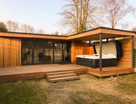 L shaped cedar clad garden room with 5 panel bifold doors, hot tub enclosure and integral shed