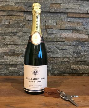 Bottle of champagne, bouquet of green and white flowers and a Robertson Garden Rooms keyring