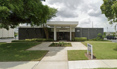 Dr. Lucas's office is in a gray brick building with green lawn and sidewalk leading to the front glass doors.