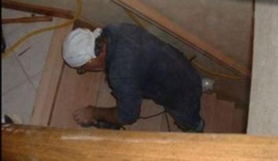 hardwood floor installer sanding stair treads.